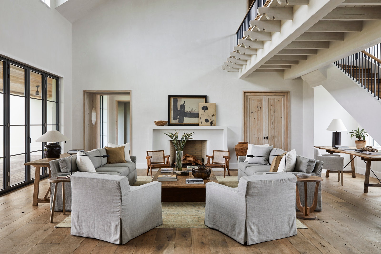 В гостиной сделанные на заказ диваны и кресла Jonas Workroom у камина антикварные кресла по дизайну Пьера Жаннере из...