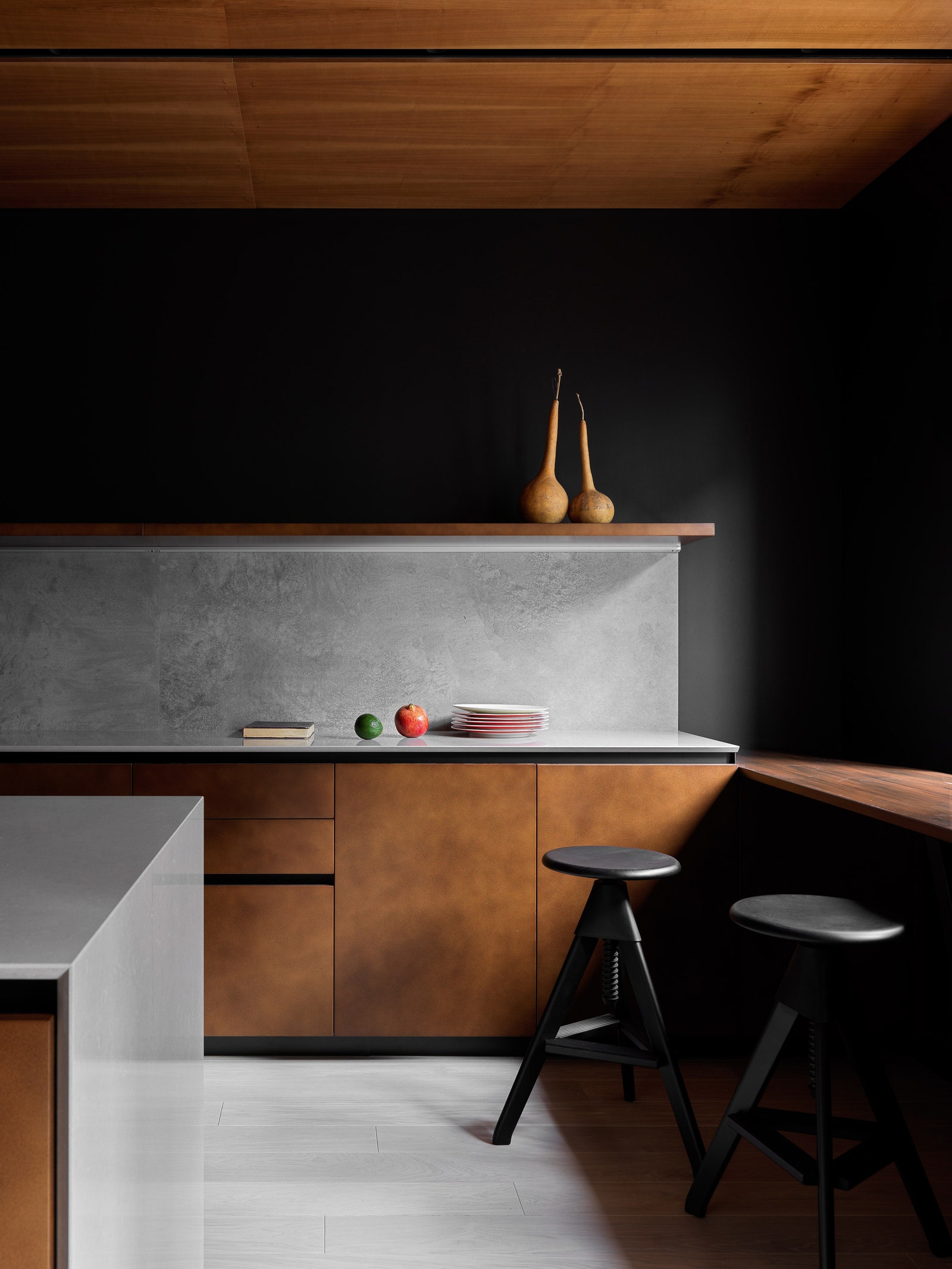 Итальянский кухон­ный гарнитур дополнен дверцами с отделкой из керамогранита. Стена за ним выкрашена в черный цвет.