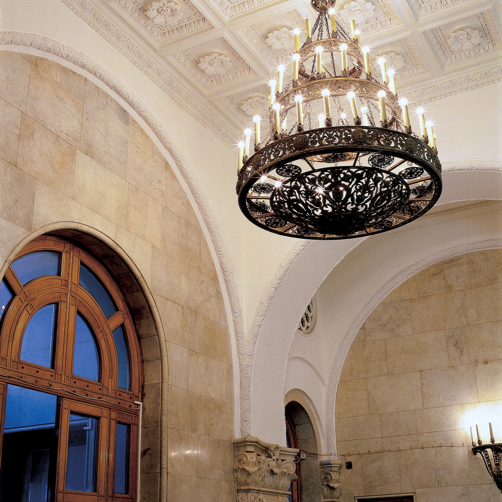 Холл высотки на Кудринской площади отделан мрамором высокие арочные двери — дубовые потолок украшен гипсовой лепниной.