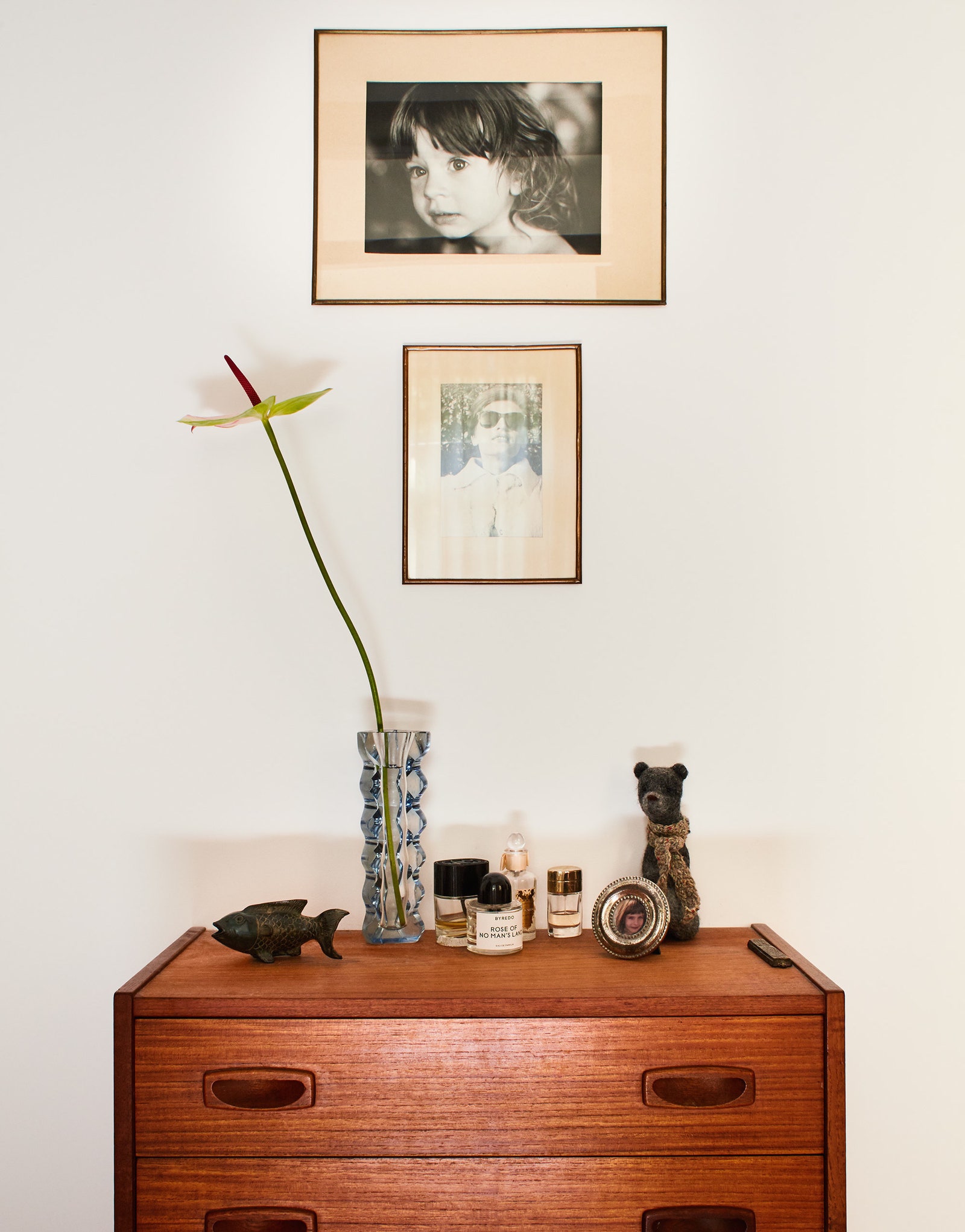 Фрагмент гостиной. Винтажный тиковый комод 1960‑х годов на стене серебряножелатиновые отпечатки семейных фотографий в...