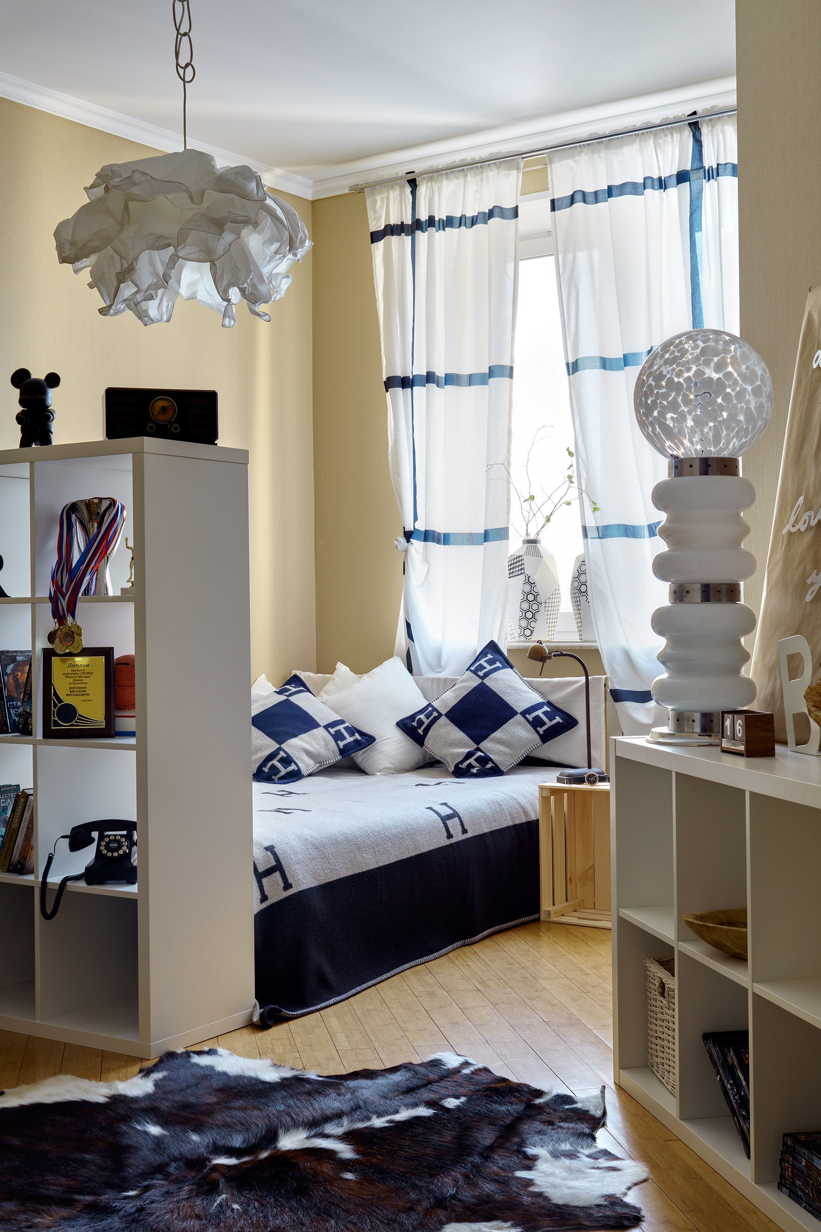 Спальня делится на две части с помощью стеллажа из IKEA. Вазы на окне из шоурума “Детали”.