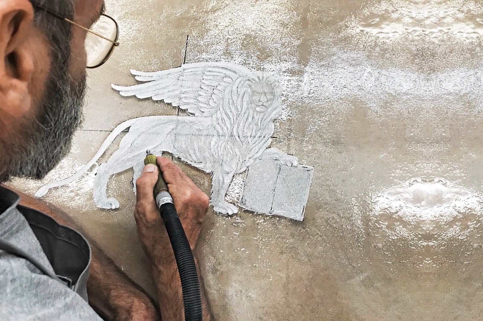 Процесс гравировки льва святого Марка на столешнице комода.