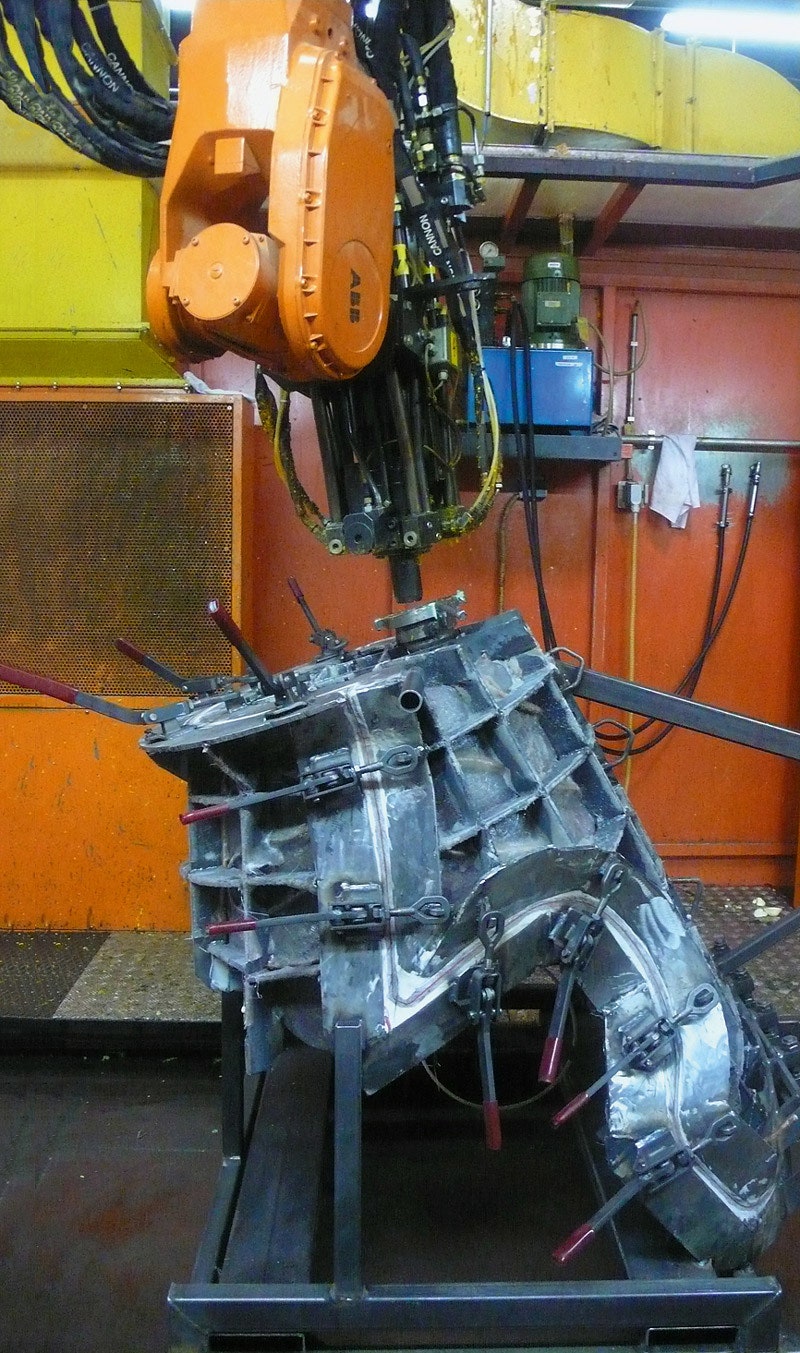 Робот вливает жидкий пенополиуретан в форму.