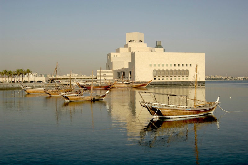 Старые лодки ловцов жемчуга на фоне Музея исламского искусства в Дохе.