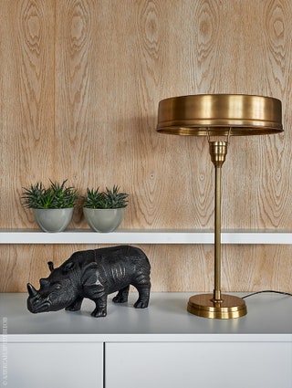 Гостиная. Настольная лампа из латуни Kare Design. Фигурка носорога Eichholtz. Белые подвесные тумбы  выполнены по...