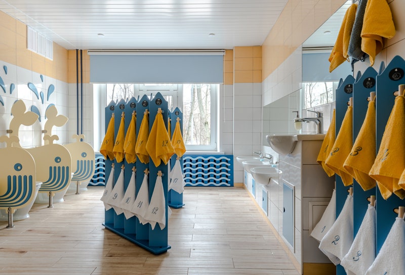 Туалет с ширмамивешалками для полотенец и экранами в виде китов разделяющими унитазы.