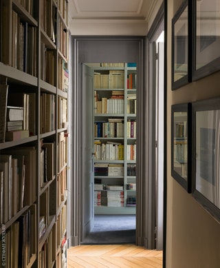 В коридоре декоратор сделала полки во всю стену чтобы добавить место для хранения документов и книг.
