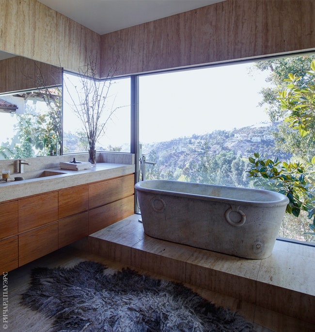 Хозяйская ванная комната с мраморной ванной на постаменте. Рядом с ней ковер из шкуры овцы по дизайну Клауди Йонгстры.