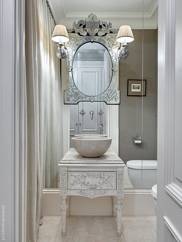 На зеркальной стене гостевого туалета прикреплено антикварное зеркало. Консоль Chelini имеет деревянную основу и...