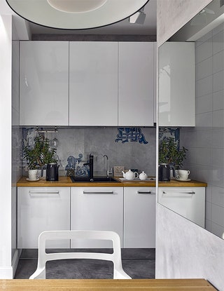 Узор на кухонном фартуке повторяет орнамент штор гостиной. Зеркальный цоколь визуально увеличивает пространство.