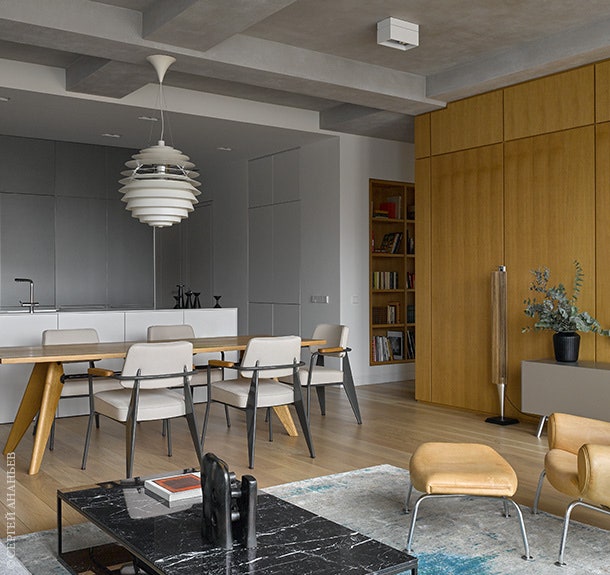 Вид на зону кухни и столовой со стороны гостиной. Стол и стулья по дизайну Жана Пруве Vitra. Журнальный столик...