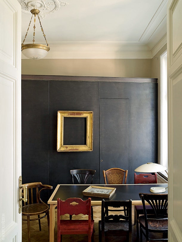 На фоне шкафов из крашенной в черный цвет фанеры — стол скандинавского дизайна и разноцветные стулья купленные на...