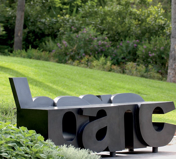 В саду перед домом стоит скульптурная скамейка в виде слова banc — в переводе с французского собственно “скамейка”.