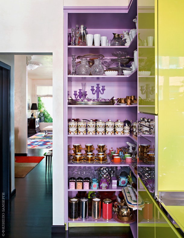 Кухня сделана довольно яркой шкафы нежного салатового оттенка лиловые стеллажи и лиловый же холодильник .