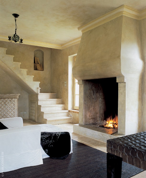 Гостиная дома декоратора Анны Гарсии в Тоскане. Стены покрыты состаренной штукатуркой. Камин лестница и столик сделаны...