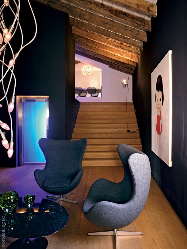 Холл первого этажа. Двери лифта подсвечены синими лампами. На стене — картина Йоситомо Нары. Кресла Egg по дизайну Арне...
