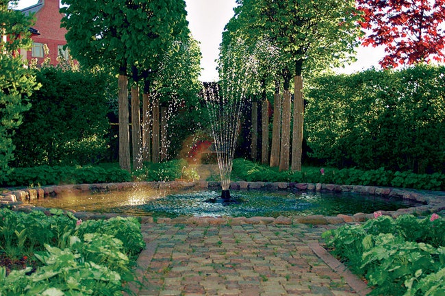 Сад в Раздорах фонтан на пересечении осей окружен живой изгородью из боярышника — она скрывает соседский забор.
