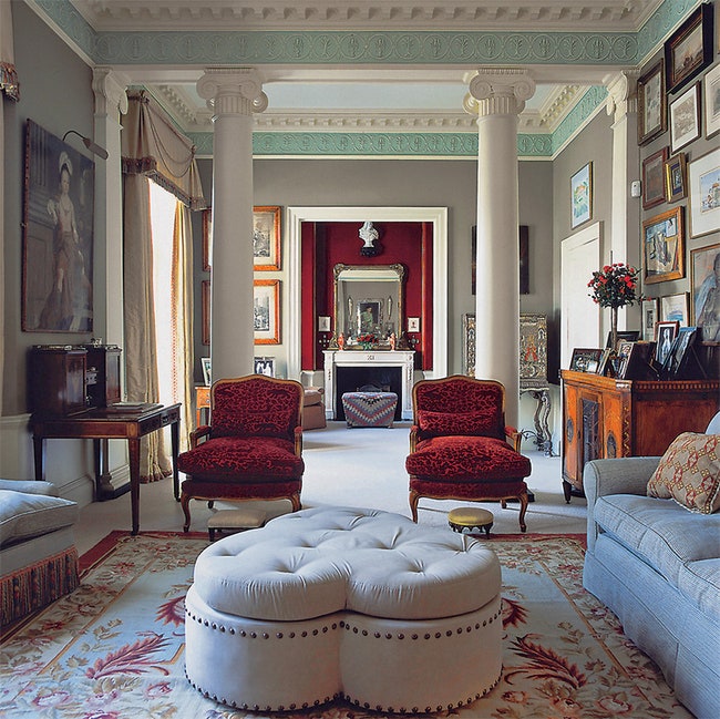 Английская гостиная большие диваны и кресла мебель из темного дерева ковер камин и картины.