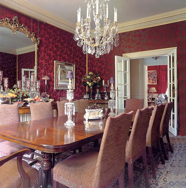 Английская столовая стол из темного дерева красные обои на стенах хрустальная люстра.