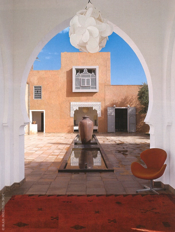 В центре дома находится патио с фонтаном. На переднем плане — берберский ковер и кресло Swan по дизайну Арне Якобсена.