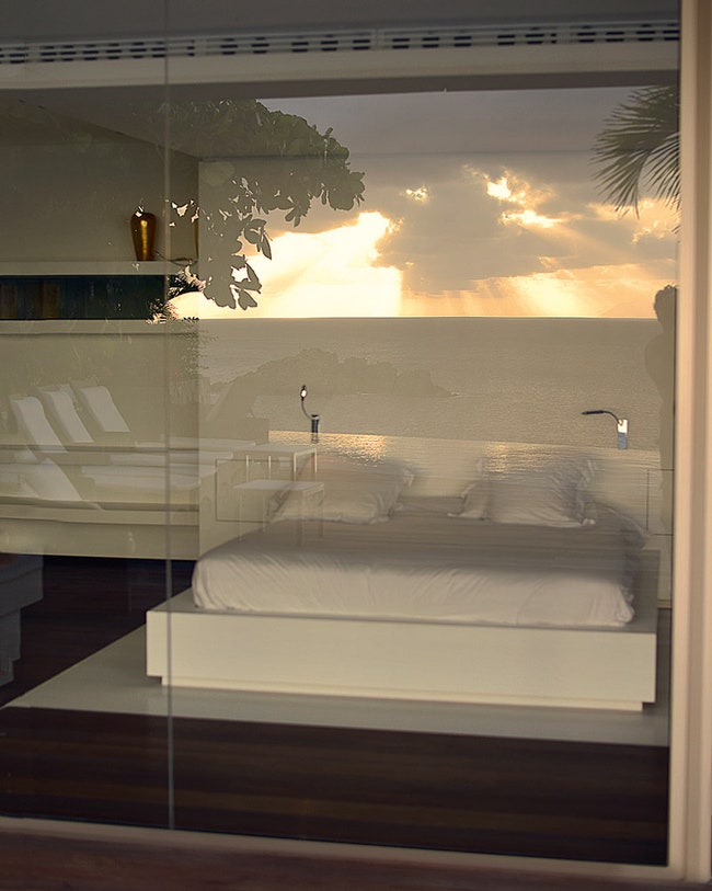 В стеклянной стене хозяйской спальни отражаются бассейн и закат над океаном.