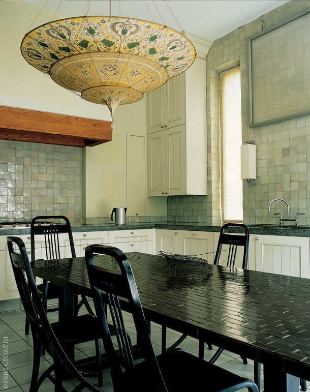 Поверхность кухонного стола сделана из керамической плитки . Стулья дизайнер Йозеф Хоффман. Люстра дизайнер Мариано Фортуни.