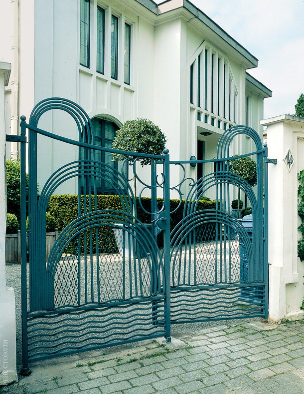 Кованые входные ворота виллы выдержаны в одном стиле со зданием.