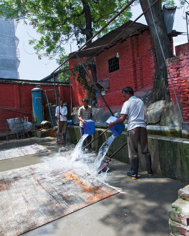 Работники моют готовые ковры.