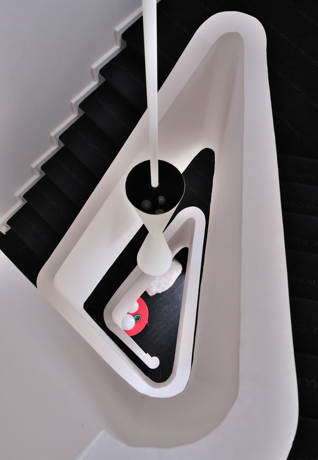 Белая округлая лест­ница и потолочный светильник по дизайну Юбера де Малерба.