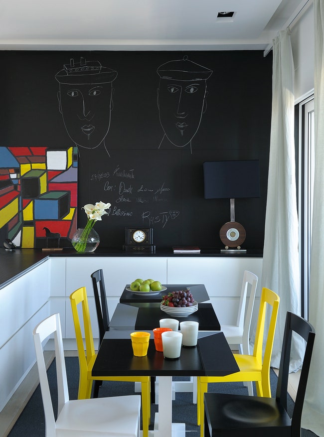 Кухня. Часть стены покрыта грифельной краской. Настольная лампа по дизайну Вилли Риццо. Деревянные столики сделаны по...