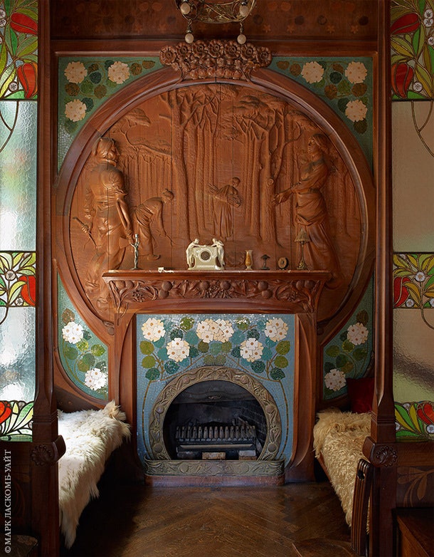 Мебель для дома в 1900х спроектировал Гаспар Омар. Камин выложен плиткой и окружен деревянной резьбой. Скамьи покрыты...