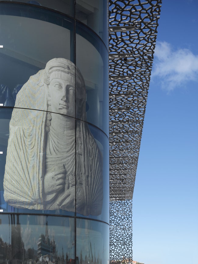 Через единственную стеклянную стену не покрытую ажурной бетонной оболочкой можно видеть экспонаты музея рассказывающие...