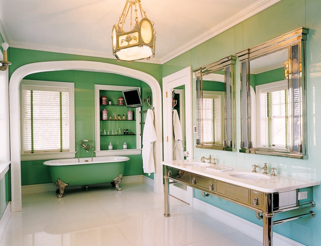 Стены просторной ванной комнаты обшиты покрашенными с обратной стороны стеклянными панелями.