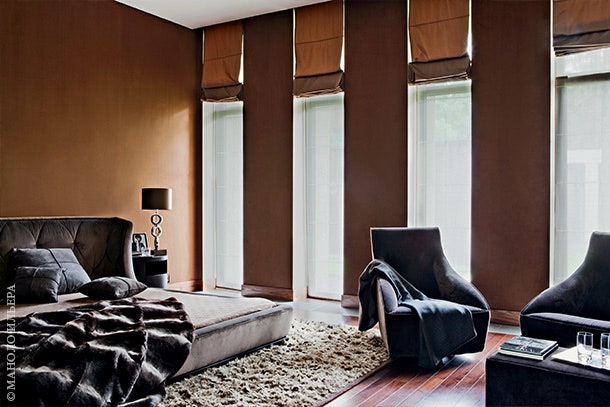 Спальня хозяев оформлена в теплых оттенках коричневого. Стены покрыты обоями напоминающими по цвету господствующий в...