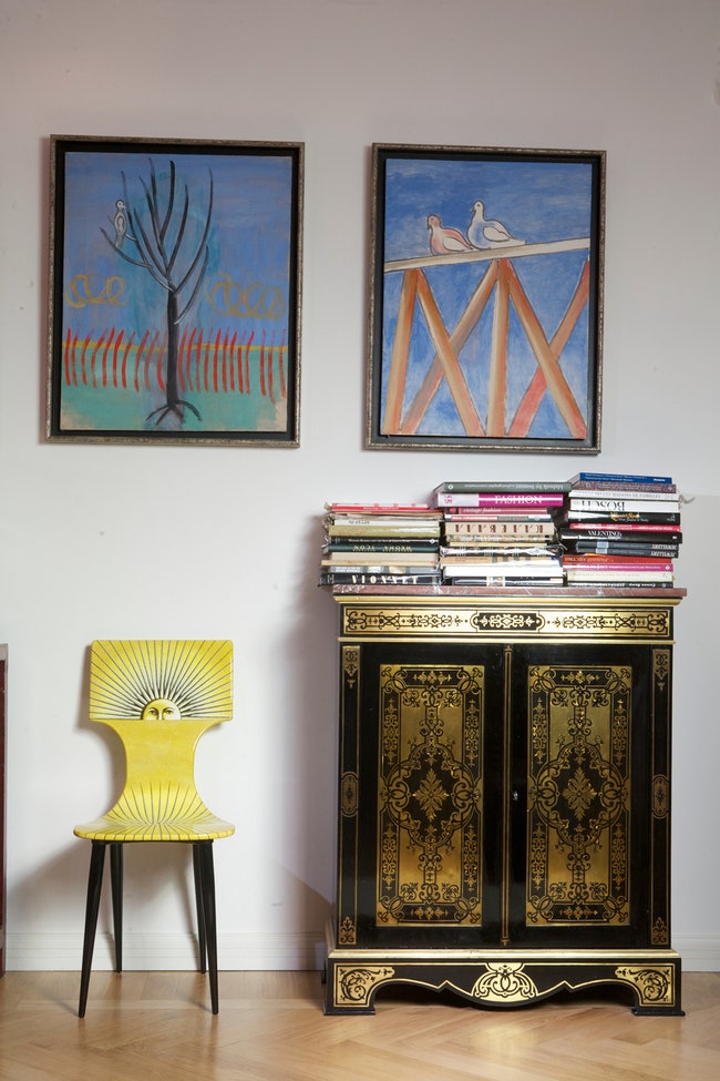 Лаковый антикварный комод соседствует со стулом Fornasetti. На стене — картины Геннадия Устюгова.
