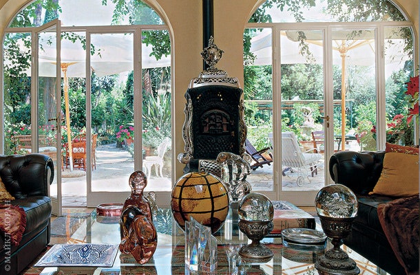 Большие стеклянные двери ведут из желтой гостиной в сад. На столе — предметы из коллекции венецианского стекла.